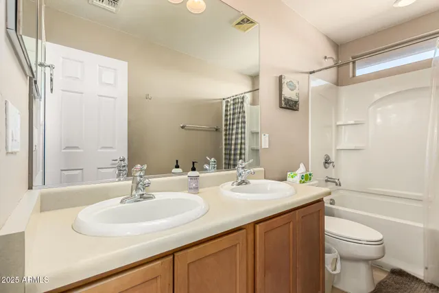a bathroom with a double vanity sink toilet and a tub