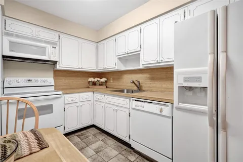 a kitchen with white cabinets and white appliances