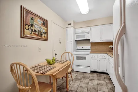 a kitchen with stainless steel appliances granite countertop a white stove a sink a dining table and chair with wooden floor