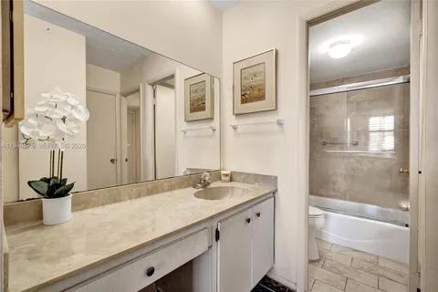a bathroom with a granite countertop sink a mirror and a shower