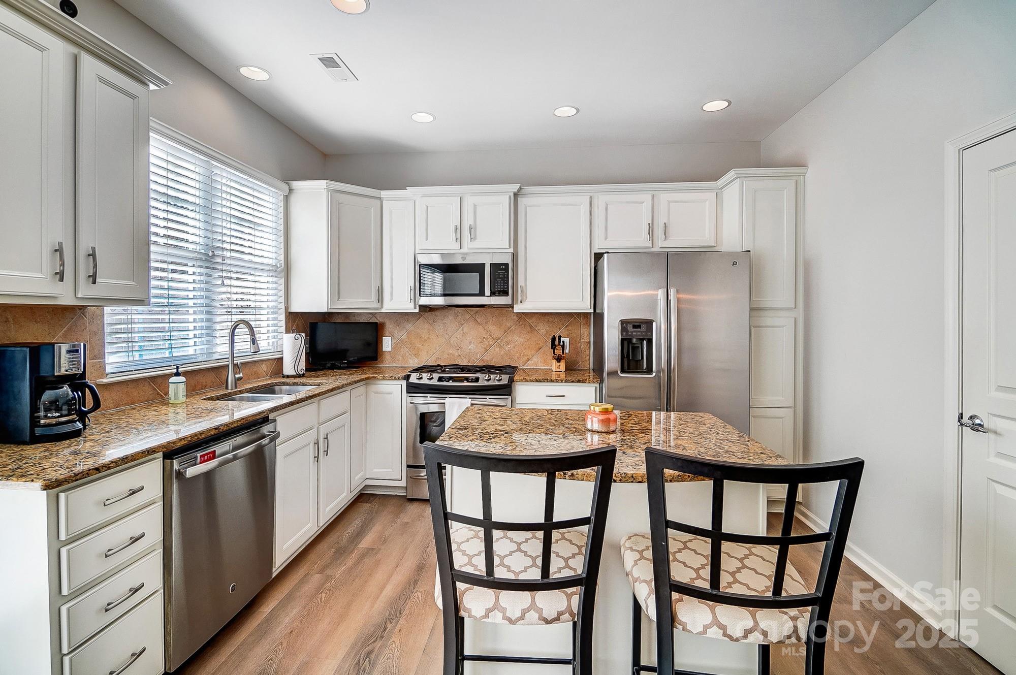582 6th Baxter Crossing Fort Mill, SC 29708 - Photo 17 of 48 a kitchen with stainless steel appliances granite countertop a stove a sink dishwasher a refrigerator and white cabinets with wooden floor