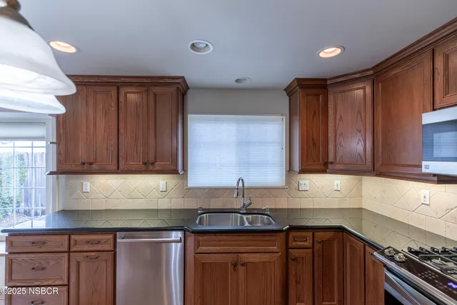 a kitchen with granite countertop a sink stove and cabinets