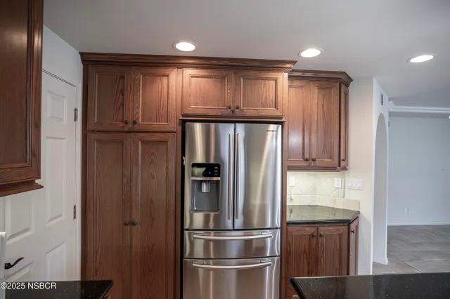 a metallic refrigerator freezer sitting inside of a kitchen