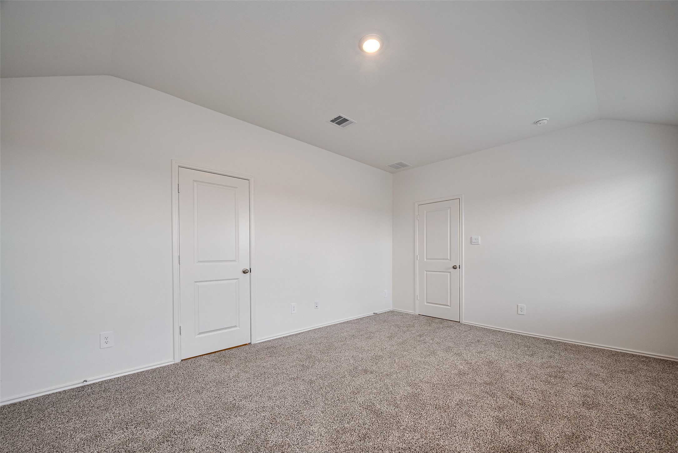 30910 Rockstock Road Fulshear, TX 77441 - Photo 26 of 33 This spacious primary bedroom features a soft sloped ceiling and expansive windows that invite in the daylight. The carpeting and airy dimensions create a serene personal space.