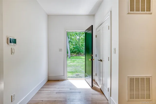 a view of hallway with a front door and wooden floor