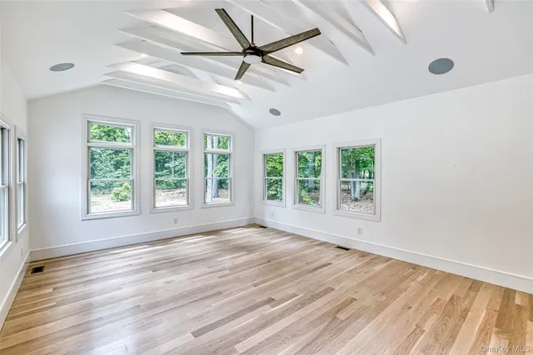 a view of an empty room with a window and wooden floor