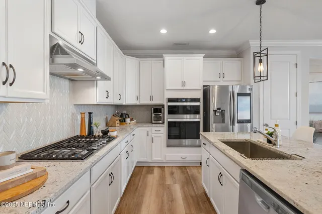 a large kitchen with stainless steel appliances granite countertop a lot of counter space and wooden floors