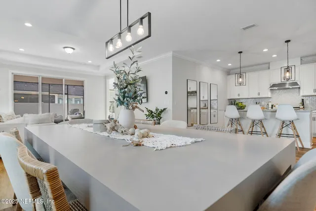 a dining room with kitchen island stainless steel appliances furniture a chandelier and kitchen view