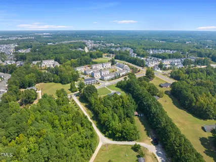 an aerial view of residential houses with outdoor space and trees