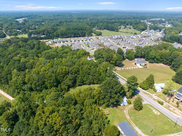 an aerial view of residential houses with outdoor space and trees