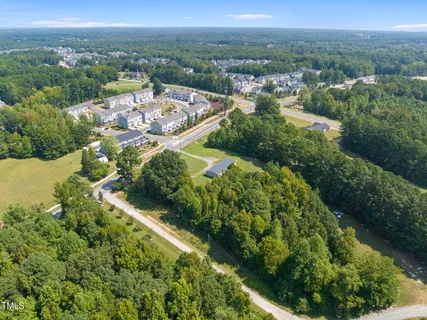 an aerial view of residential house with outdoor space and trees all around