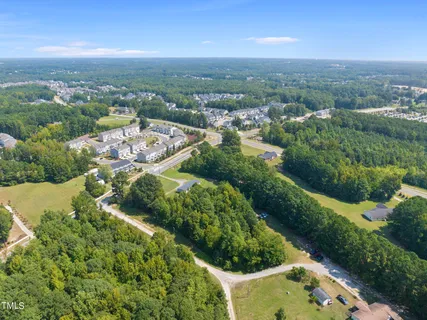 an aerial view of residential houses with outdoor space and trees