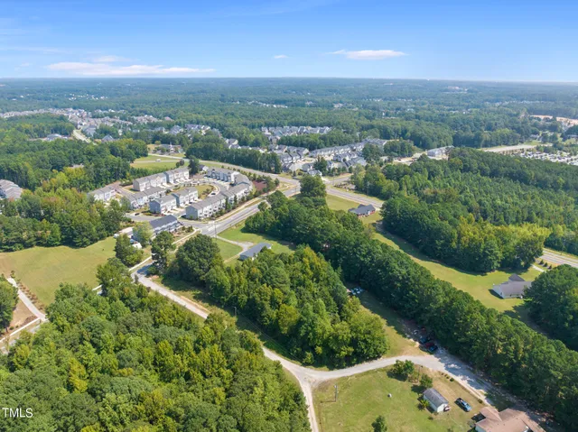 an aerial view of residential houses with outdoor space and trees