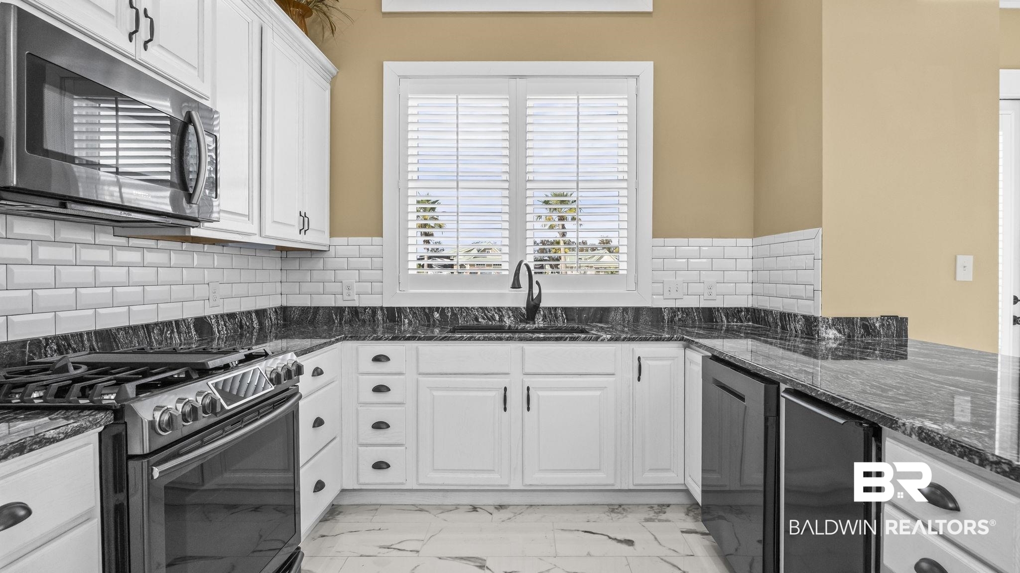 12004 Raptor Court Elberta, AL 36530 - Photo 12 of 57 Kitchen with gas range oven, light marble finish floors, stainless steel microwave, white cabinets, and dark stone countertops