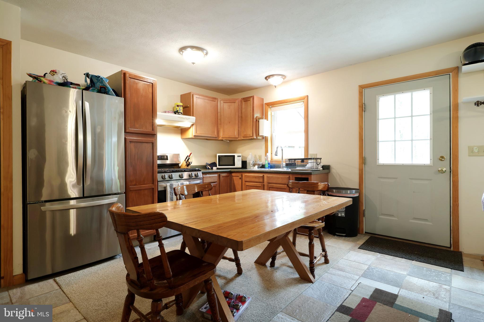 358 Buckridge Road Howard, PA 16841 - Photo 12 of 40 a kitchen with stainless steel appliances granite countertop a dining table chairs refrigerator and window