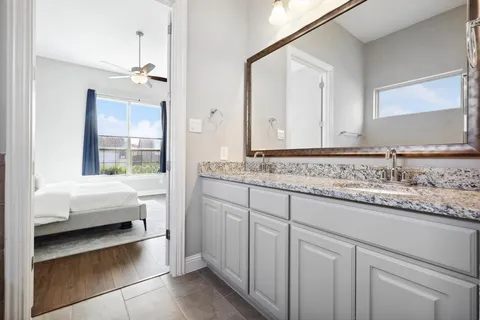 a en suite bathroom with a granite countertop sink and a mirror