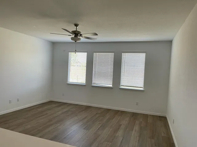 an empty room with a window and a ceiling fan