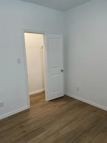 a view of an empty room with wooden floor and closet