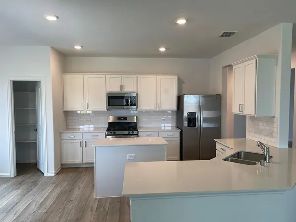 a kitchen with stainless steel appliances granite countertop a refrigerator a stove top oven a sink and dishwasher