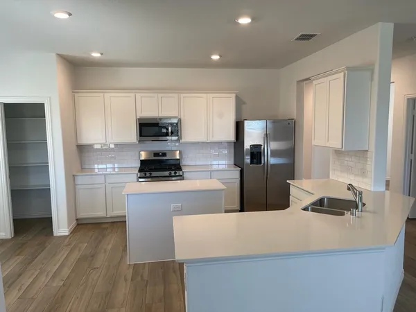 a kitchen with kitchen island a counter top space a sink a refrigerator and a stove