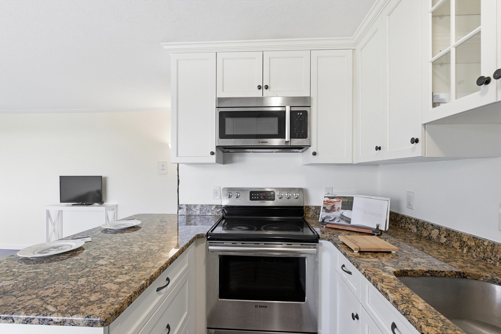 125 Trapelo Road, Unit U23 Belmont, MA 02478 - Photo 5 of 18 a kitchen with granite countertop a sink stove and microwave