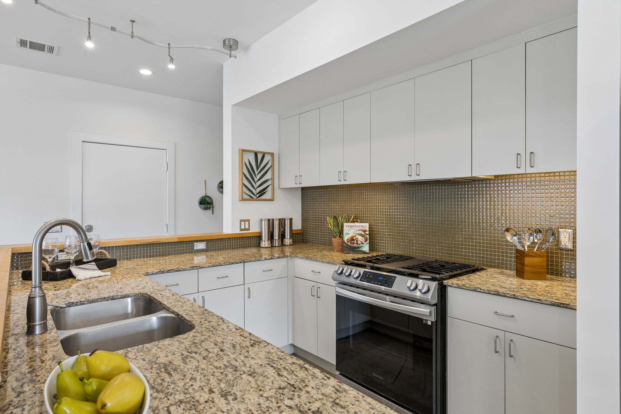 5305 Guadalupe Street, Unit A Austin, TX 78751 - Photo 6 of 31 Kitchen with stainless steel gas stove, white cabinetry, light stone counters, backsplash, and under cabinet lighting
