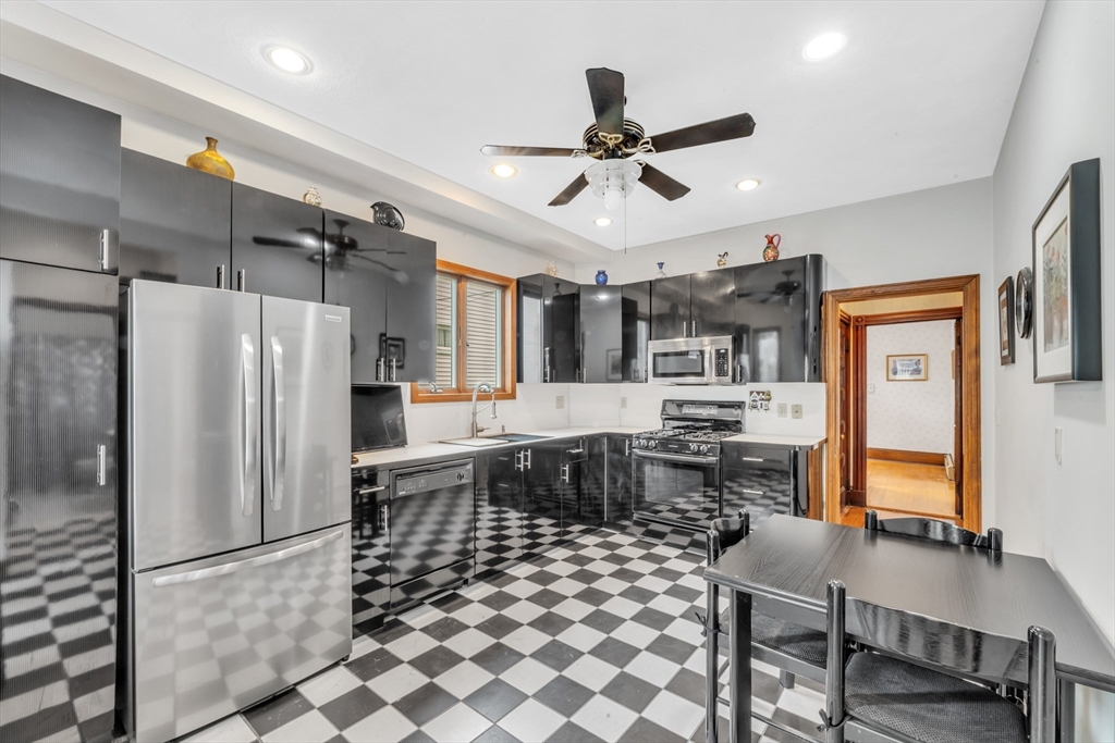196 Maple Street Boston, MA 02132 - Photo 9 of 33 a kitchen with stainless steel appliances a refrigerator a stove a sink dishwasher a dining table and chairs with wooden floor