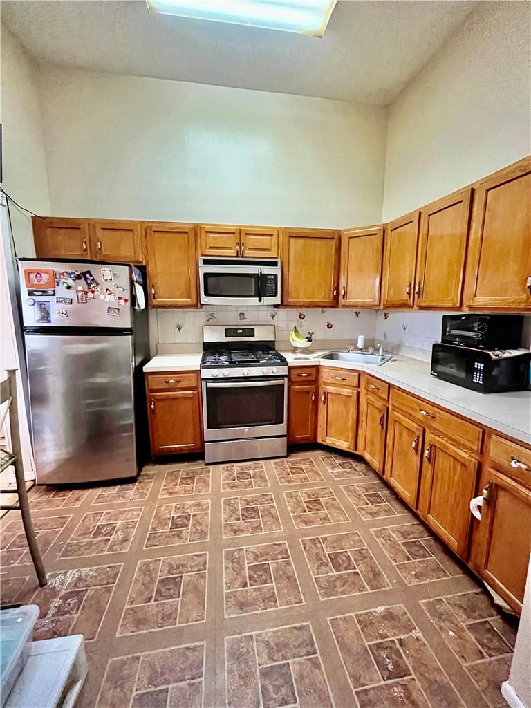 1012 East 172nd Street Bronx, NY 10460 - Photo 8 of 25 Kitchen with appliances with stainless steel finishes, a towering ceiling, tasteful backsplash, and sink