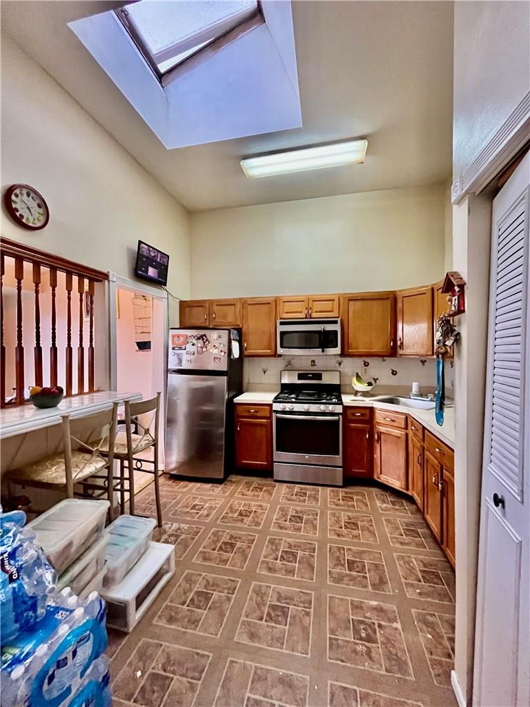 1012 East 172nd Street Bronx, NY 10460 - Photo 9 of 25 Kitchen with high vaulted ceiling, sink, stainless steel appliances, and a skylight