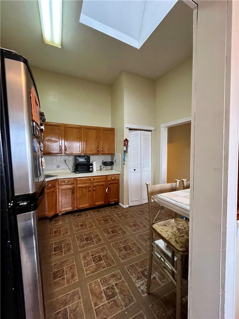 1012 East 172nd Street Bronx, NY 10460 - Photo 10 of 25 Kitchen featuring stainless steel refrigerator, a skylight, dark tile patterned floors, decorative backsplash, and a high ceiling