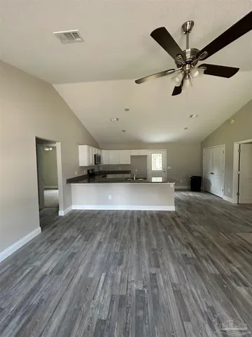 a view of empty room with wooden floor and ceiling fan