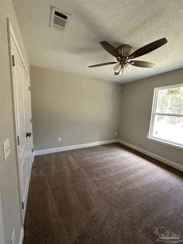 en empty room with windows and ceiling fan