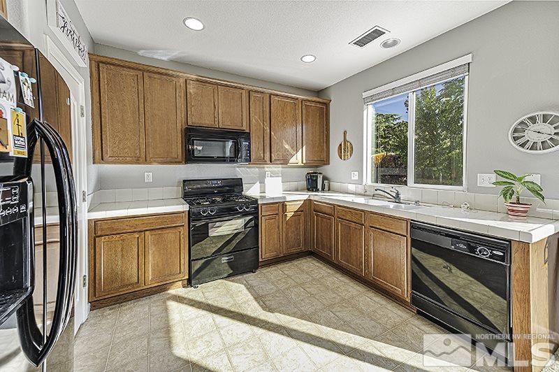 340 Manciano Way Reno, NV 89521 - Photo 5 of 15 a kitchen with stainless steel appliances granite countertop a stove a sink dishwasher a refrigerator and a microwave oven