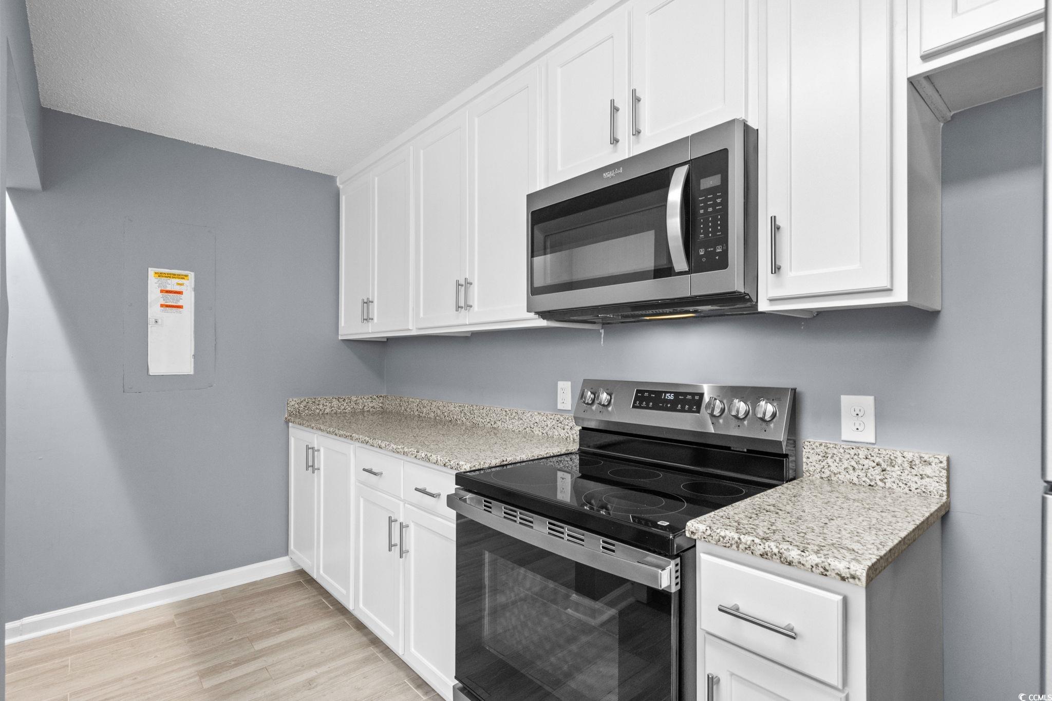 3343 New Road Conway, SC 29527 - Photo 11 of 36 Kitchen featuring appliances with stainless steel finishes, white cabinets, light stone countertops, and light wood-type flooring