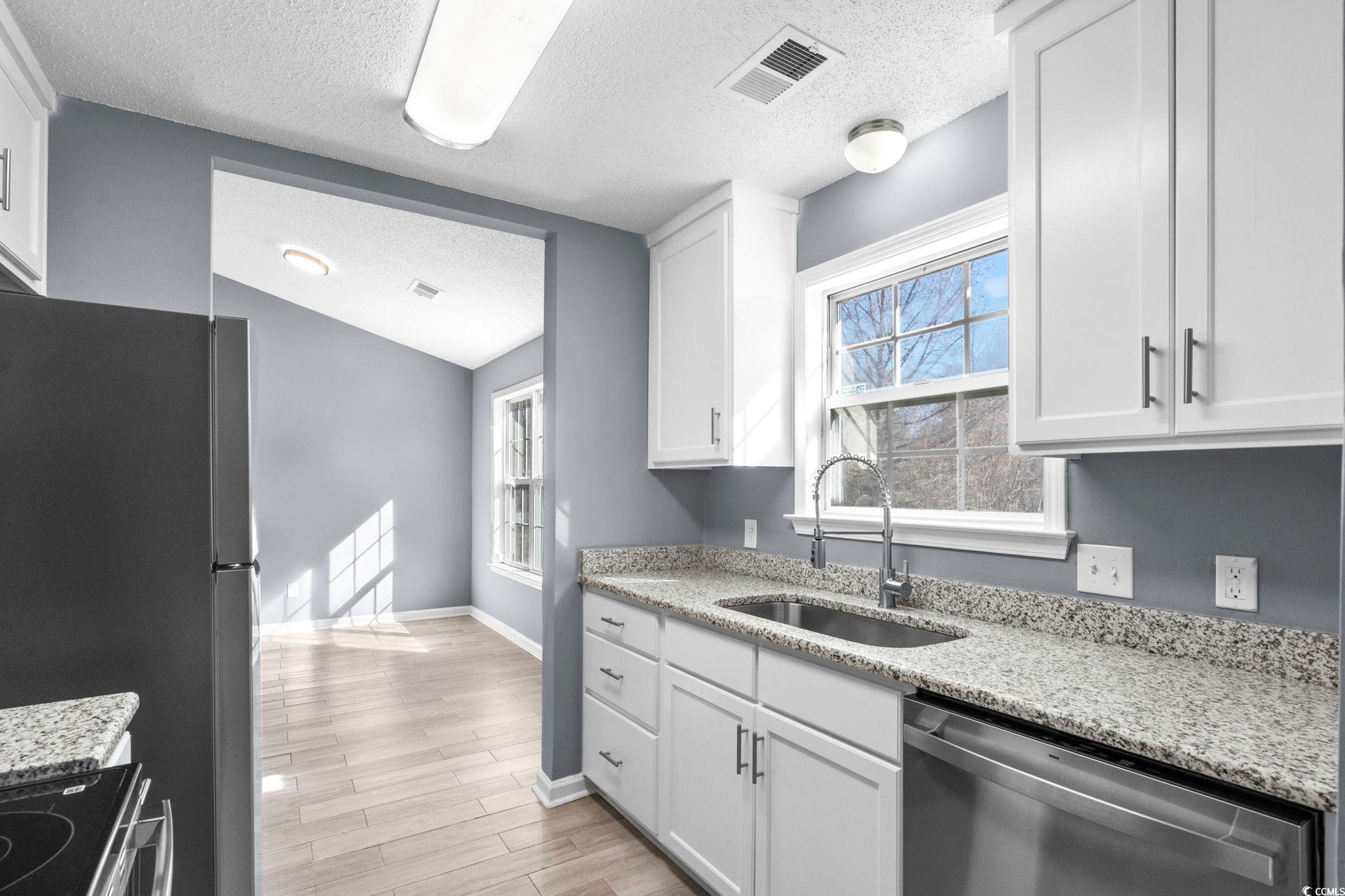 3343 New Road Conway, SC 29527 - Photo 14 of 36 Kitchen featuring stainless steel dishwasher, light stone counters, a textured ceiling, white cabinetry, and healthy amount of natural light