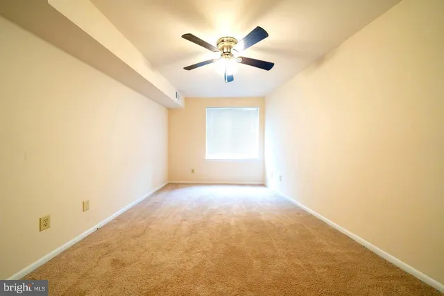 an empty room with chandelier fan and windows