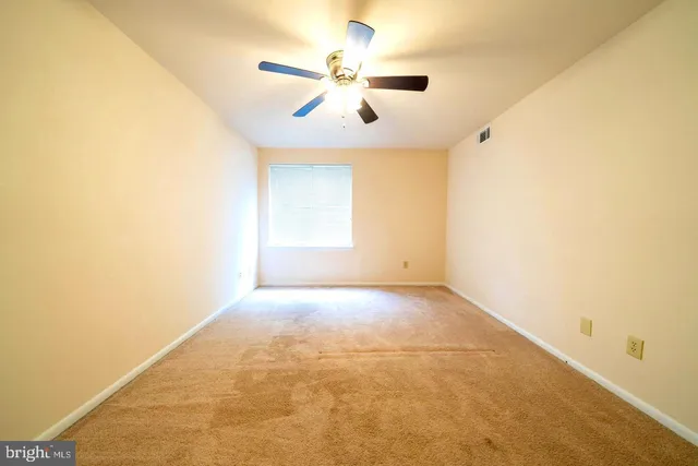 an empty room with windows and ceiling fan