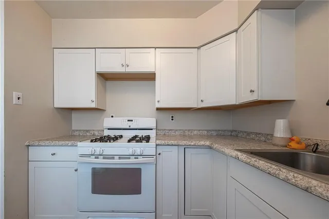 a kitchen with granite countertop white cabinets and white appliances