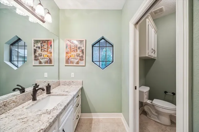 a bathroom with a granite countertop sink vanity mirror and toilet