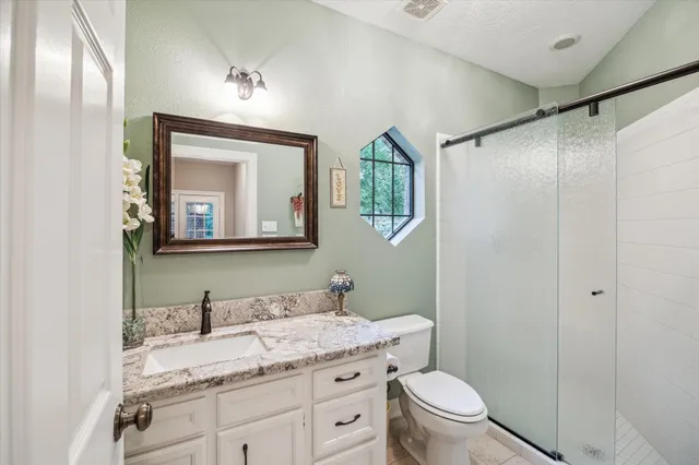 a bathroom with a granite countertop sink toilet and mirror