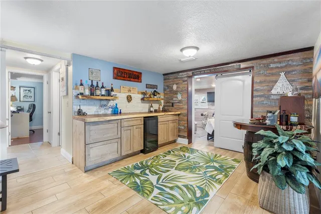 a kitchen with a stove a sink dishwasher a refrigerator cabinets and a dining table with wooden floor