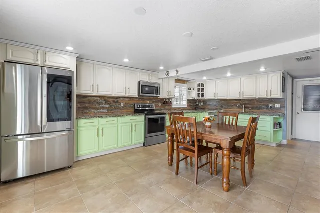 a kitchen with kitchen island a refrigerator and a dining table
