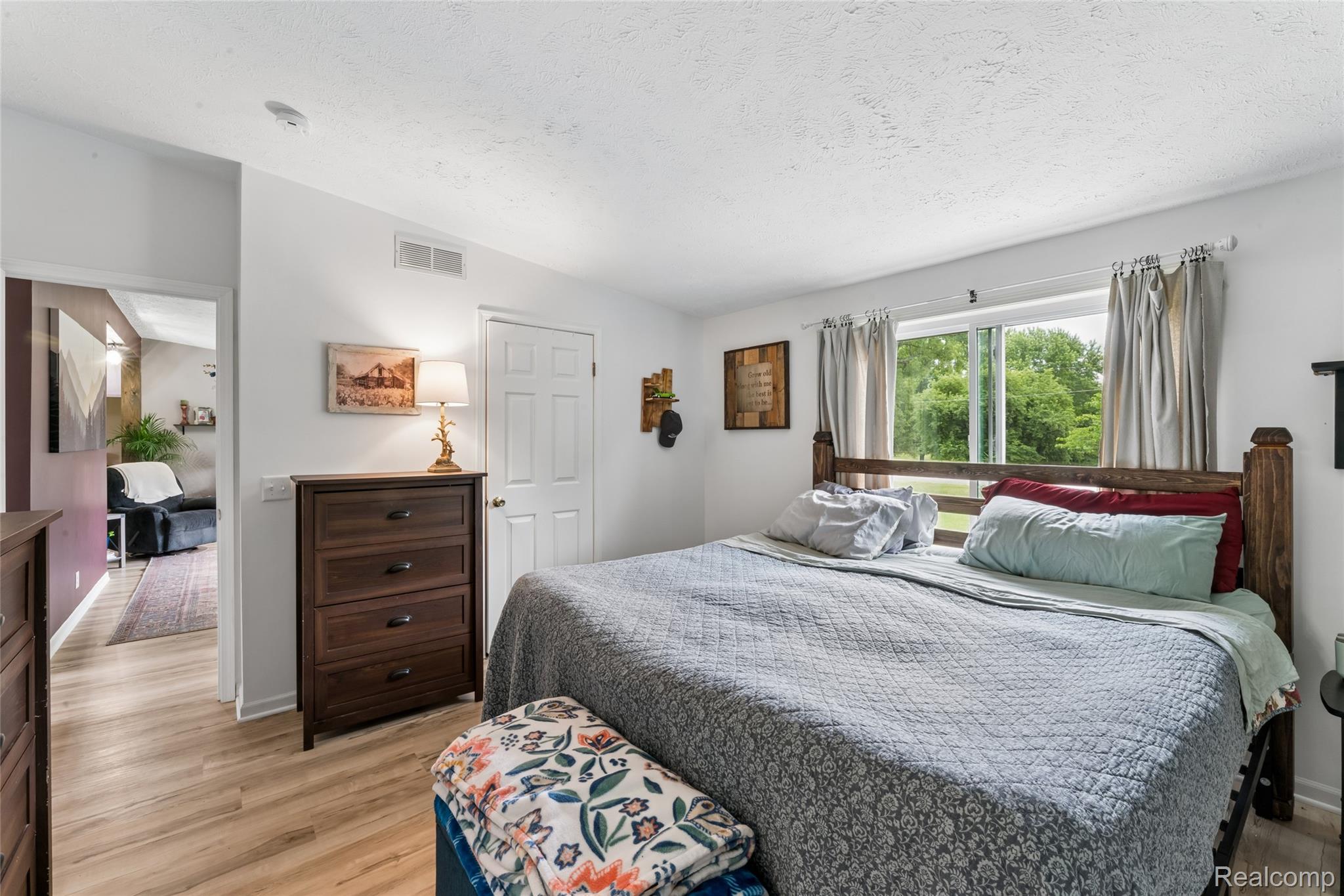 1336 West Hurd Road Clio, MI 48420 - Photo 24 of 43 Bedroom featuring light-tone wood-finish flooring, a white interior door, and a horizontal window with exterior tree views