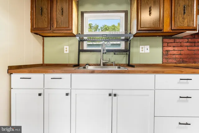 a kitchen with stainless steel appliances granite countertop white cabinets and a window