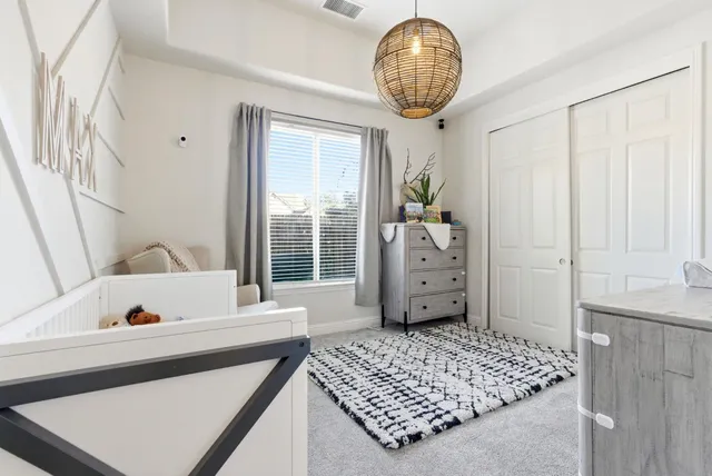 a bedroom with a large bed and a chandelier next to a window