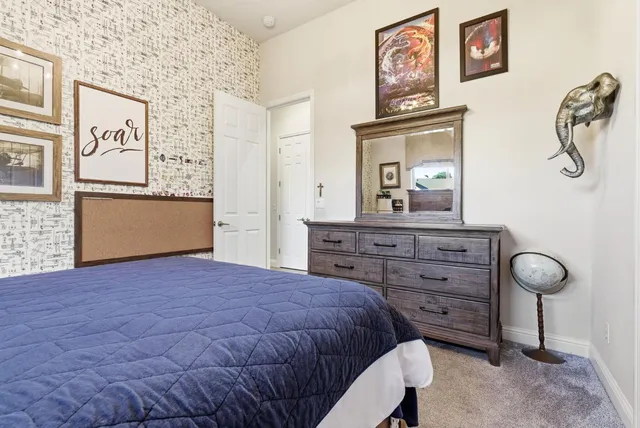 a bedroom with a bed and a flat tv screen on dresser