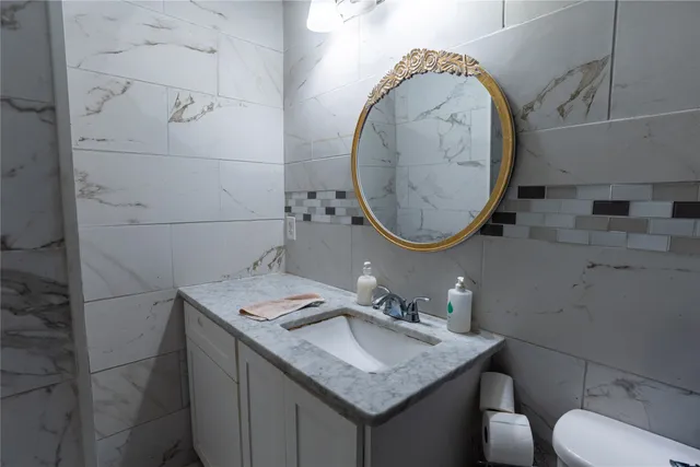 a bathroom with a granite countertop sink a mirror and toilet