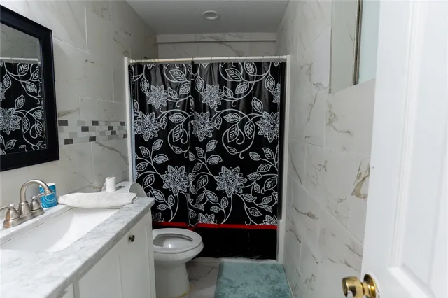 a bathroom with a granite countertop toilet and a sink