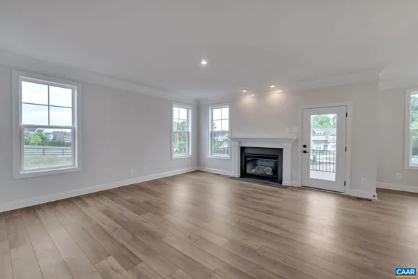 a view of an empty room with wooden floor and a fireplace