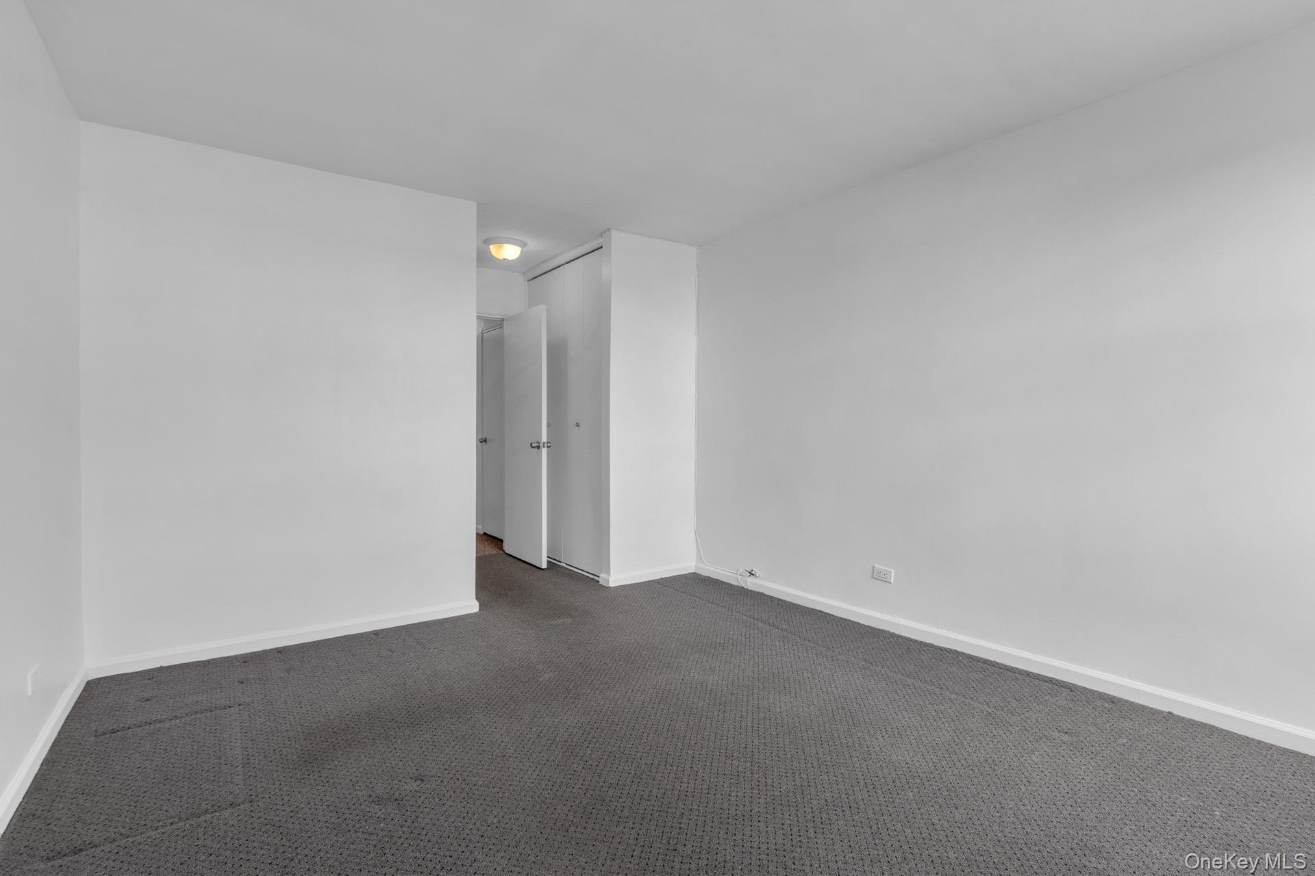 211-40 18th Avenue, Unit 6C Queens, NY 11360 - Photo 26 of 41 Empty room featuring dark colored carpet and baseboards